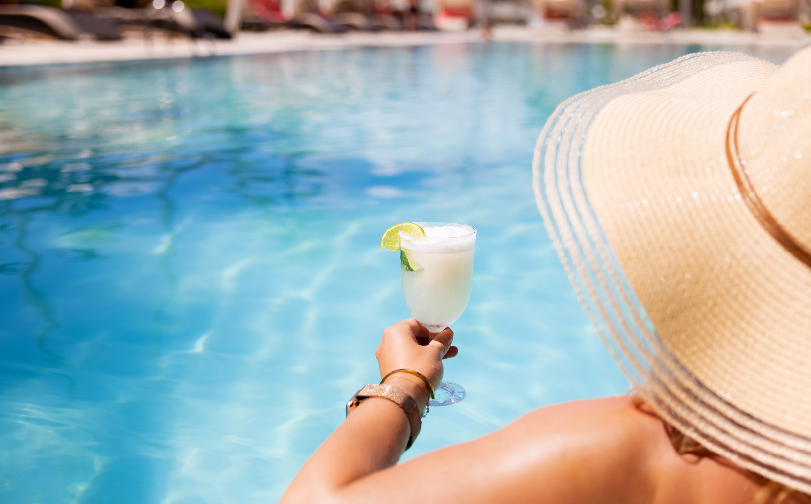 Woman Relaxing by Poolside and Holding Glass of Cocktail in Luxury All-Inclusive Tropical Resort